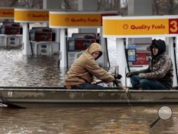 Paul Dusablon, left, and Richard Kotva row from the Circle K at Springdale Park after helping the owner move electronics off the floor inside the convenience store, in Fenton, Mo., Wednesday, Dec. 30, 2015. A rare winter flood threatened nearly two dozen federal levees in Missouri and Illinois as rivers rose, prompting evacuations in several places. (Robert Cohen/St. Louis Post-Dispatch via AP)