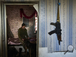 A Ukrainian soldier pets a dog as he rests inside a house near Bakhmut, Donetsk region, Ukraine, Thursday, Dec. 22, 2022. (AP Photo/Libkos)