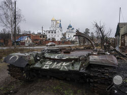 A destroyed Russian tank stands across the road of a church in the town of Sviatohirsk, Ukraine, Friday, Jan. 6, 2023. (AP Photo/Evgeniy Maloletka)