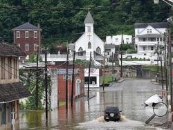 A vehicle makes a wake along the flooded Lower Oakford Ave. Friday, June 24, 2016, in Richwood, W.Va. (Rick Barbero/The Register-Herald)