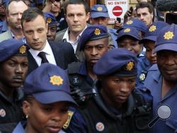 Escorted by police and security, Oscar Pistorius leaves the court in Pretoria, South Africa, Friday, Sept. 12, 2014. In passing judgement judge Thokozile Masipa ruled out a murder conviction for the double-amputee Olympian in the shooting death of his girlfriend, Reeva Steenkamp, but said he was negligent and convicted him of culpable homicide. Sentencing is scheduled for Oct. 13, 2014. (AP Photo/Jerome Delay)