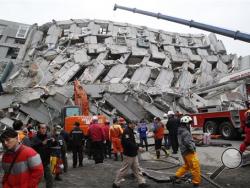 Rescue workers search a collapsed building from an early morning earthquake in Tainan, Taiwan, Saturday, Feb. 6, 2016. A powerful, shallow earthquake struck southern Taiwan before dawn Saturday. (AP Photo/Wally Santana)