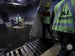 New Jersey Transit workers lay down pallets and boards for commuters to walk on a flooded hallway adjacent to the site of a train crash at the Hoboken Terminal, Friday, Sept. 30, 2016, in Hoboken, N.J. Commuters are using alternative travel in and out of Hoboken a day after a commuter train crashed into the rail station, killing one person and injuring more than 100 people. (AP Photo/Julio Cortez)