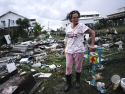 Jewell Baggett stands beside a Christmas decoration she recovered from the wreckage of her mother’s home, as she searches for anything salvageable from the trailer home her grandfather had acquired in 1973 and built multiple additions on to over the decades, in Horseshoe Beach, Fla., after the passage of Hurricane Idalia, Wednesday, Aug. 30, 2023. (AP Photo/Rebecca Blackwell)