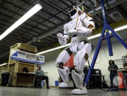In this May 2, 2016 photo, researchers watch a six-foot-tall, 300-pound Valkyrie robot walk slowly at University of Massachusetts-Lowell's robotics center in Lowell, Mass. NASA spokesman Jay Bolden says the agency aims to get to Mars by 2035 and it’ll be the Valkyries or their descendants paving the way. (AP Photo/Elise Amendola)