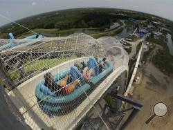 In this photo taken with the fisheye lens, riders go down the world's tallest water slide called "Verruckt" at Schlitterbahn Waterpark, Wednesday, July 9, 2014, in Kansas City, Kan. The 168-foot-tall waterslide is scheduled to open to the public Thursday, after initially being slated to open May 23. (AP Photo/Charlie Riedel)