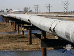 FILE - In this 2007 file photo, an oil transit pipeline runs across the tundra to flow station at the Prudhoe Bay oil field on Alaska's North Slope.The Obama administration is blocking new oil and gas drilling in the Arctic Ocean, handing a victory to environmentalists who say industrial activity in the icy waters will harm marine mammals and exacerbate global warming. (AP Photo/Al Grillo, File)