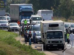 Police stand near a truck that stands on the shoulder of the highway A4 near Parndorf south of Vienna, Austria, Thursday, Aug 27, 2015. At least 20 migrants were found dead in the truck parked on the Austrian highway leading from the Hungarian border, police said. (AP Photo/Ronald Zak)