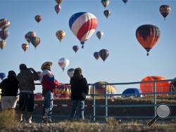 Standing on the North Diversion Channel path, Raul Granillo, third from left, gazes up as the hot air balloons that took part in the annual Albuquerque International Balloon Fiesta in Albuquerque, N.M. Saturday, Oct. 4, 2014. (AP Photo/The Albuquerque Journal, Jim Thompson)