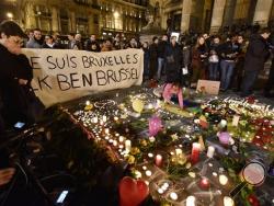 People holding a banner reading "I am Brussels" behind flowers and candles to mourn for the victims at Place de la Bourse in the center of Brussels, Tuesday, March 22, 2016. Bombs exploded at the Brussels airport and one of the city's metro stations Tuesday, killing and wounding scores of people, as a European capital was again locked down amid heightened security threats. (AP Photo/Martin Meissner)
