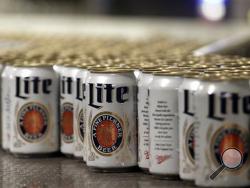 In this March 11, 2015 photo, newly-filled and sealed cans of Miller Lite beer move along on a conveyor belt, at the MillerCoors Brewery, in Golden, Colo. (AP Photo/Brennan Linsley)