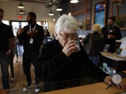In this Feb. 19, 2019 photo, Sandy Sopher, 65, smells cannabis buds at Bud and Bloom cannabis dispensary in Santa Ana, Calif. As legal cannabis has spread to dozens of states, more Americans in their 70s and 80s are adding marijuana to the roster of senior activities such as golf and bingo. (AP Photo/Jae C. Hong)