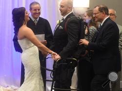 Jordan Basile, left, and Matt Ficarra, center, exchange wedding vows Saturday, Oct. 18, 2014, at the Doubletree hotel in Syracuse, N.Y. Presiding over the ceremony is Ted Limpert. Ficarra, who was paralyzed in an accident in 2011, used a robotic-like device called an Ekso with the help of Nicole Smith, second right, and Frank Hyland from Good Shepard in Allenton Pa. (AP Photo/The Syracuse Newspapers, Dennis Nett) 