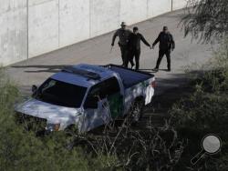 In this Wednesday, Nov. 16, 2016, photo, a U.S. Customs and Border Patrol agent walks with suspected immigrants caught entering the country illegally along the Rio Grande in Hidalgo, Texas. (AP Photo/Eric Gay)