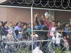 Central American migrants wait for food in El Paso, Texas, Wednesday, March 27, 2019, in a pen erected by U.S. Customs and Border Protection to process a surge of migrant families and unaccompanied minors. Earlier, Customs and Border Protection Commissioner Kevin McAleenan, center, announced the the Trump administration will temporarily reassign several hundred border inspectors, during a news conference at the border in El Paso. (AP Photo/Cedar Attanasio)