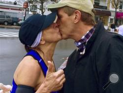 In this April 20, 2015 photo provided by Paige Tatge, her mother, Barbara Tatge, left, kisses an unknown spectator in Wellesley, Mass., as she ran in the Boston Marathon.