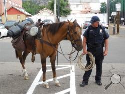 Boulder police look after a horse after its rider was arrested on four charges, including suspicion of riding under the influence and animal cruelty, Monday, Sept. 9, 2013, in Boulder, Colo. (AP Photo/Daily Camera, Mitchell Byars)