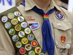 FILE - Merit badges and a rainbow-colored neckerchief slider are affixed on a Boy Scout uniform outside the headquarters of Amazon in Seattle. The U.S. organization, which now welcomes girls into the program and allows them to work toward the coveted Eagle Scout rank, announced Tuesday, May 7, 2024, that it will change its name to Scouting America as it focuses on inclusion. (AP Photo/Ted S. Warren, File)