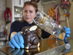 Niaz Mardan wraps a luxury handmade Belgian chocolate rabbit at Sandrine a chocolate shop in south west London, Thursday, March 21, 2024. Niaz Mardan, is suffering due to high cocoa prices, she's making no profits and fears she will have to close the shop that's been around for 25 years (she's the third owner and took over in 2019). (AP Photo/Kirsty Wigglesworth)