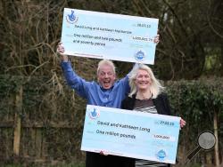David and Kathleen Long pose for a photograph with their symbolic cheques from the British lottery at The Mallard in Scunthorpe, England. (AP Photo/PA, Lynne Cameron) 