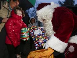 In this Dec. 17, 2015, file photo, Safyre Terry receives packages from Santa Claus in Rotterdam, N.Y. Terry, who lost her father and siblings in an arson fire that left her severely scarred is sharing the good cheer bestowed on her by the truckload since her simple Christmas wish went viral. (AP Photo/Mike Groll, File)