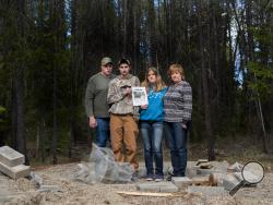 Moose Hempel, left, stands with his children, Tyler and Kayla and wife Chris, at the site where their cabin used to stand on Wednesday, April 8, 2015, near Springdale, Wash. (AP Photo/The Spokesman-Review, Tyler Tjomsland)