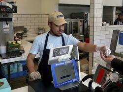 An employee collects payment at an Auntie Anne's and Cinnabon store in Livermore, Calif., Thursday, March 28, 2024. He's among hundreds of thousands of California fast-food workers who will be paid at least $20 an hour starting Monday, April 1. (AP Photo/Terry Chea)