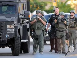 Authorities search an area Wednesday, Dec. 2, 2015, following a shooting that killed multiple people at a social services center for the disabled in San Bernardino, Calif. (James Quigg/The Victor Valley Daily Press via AP) 
