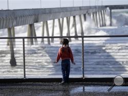 Eliki Bastow, 6, visiting from Cambridge, England, watches waves crash on the municipal pier Friday, Dec. 11, 2015, in Pacifica, Calif. The biggest storm to hit the slopes of the Sierra Nevada this season triggered cheers Friday from the snow-starved ski resorts of Northern California and the businesses that surround them. (AP Photo/Marcio Jose Sanchez)