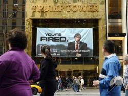 In this Saturday, March 27, 2004 file photo, passersby look at a sign advertising the reality television show, "The Apprentice," displayed at the entrance to the Trump Tower building in New York. (AP Photo/Bebeto Matthews)