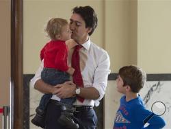 Liberal leader Justin Trudeau kisses his son, Hadrien, as son Xavier looks on while they wait to vote at a polling station Monday, Oct. 19, 2015 in Montreal. Canadians voted Monday to decide whether to extend Conservative Prime Minister Stephen Harper's near-decade in power or return Canada to its more liberal roots. (Adrian Wyld/The Canadian Press via AP) M