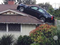 This photo released by the Glendale Police Department shows a black Cadillac that lost control and careened onto the roof of a neighbor's home on Saturday, March 23, 2013 in Glendale, Calif. The Cadillac driver lost control before leaving his driveway, plunging off a hill "onto the roof of his neighbor's house directly below his driveway. (Photo courtesy of Glendale Police Department)