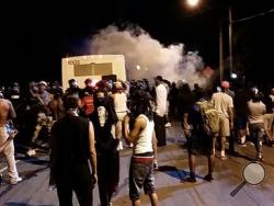 Police fire tear gas into the crowd of protesters on Old Concord Road late Tuesday night, Sept. 20, 2016, in Charlotte, N.C. A black police officer shot an armed black man at an apartment complex Tuesday, authorities said, prompting angry street protests late into the night. The Charlotte-Mecklenburg Police Department tweeted that demonstrators were destroying marked police vehicles and that approximately 12 officers had been injured, including one who was hit in the face with a rock. (Ely Portillo/The Char