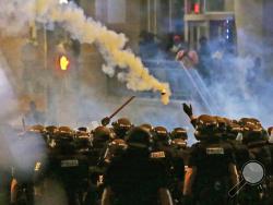 Police fire tear gas as protestors converge downtown following Tuesday's police shooting of Keith Lamont Scott in Charlotte, N.C., Wednesday, Sept. 21, 2016. Protesters have rushed police in riot gear at a downtown Charlotte hotel and officers have fired tear gas to disperse the crowd. At least one person was injured in the confrontation, though it wasn't immediately clear how. Firefighters rushed in to pull the man to a waiting ambulance.(AP Photo/Gerry Broome)