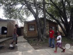 Kids play Friday April 29, 2016 in front of the townhouse at 8105 Chipping in San Antonio, Texas, where children were allegedly chained up in the back yard. (John Davenport/The San Antonio Express-News via AP)