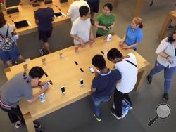 Customers look at Apple iPhone SE and 6S models on display at an Apple Store in Beijing, Saturday, June 18, 2016. A Chinese regulator has ordered Apple Inc. to stop selling two versions of its iPhone 6 in the city of Beijing after finding it looks too much like a competitor, but Apple says sales are going ahead while it appeals. (AP Photo/Mark Schiefelbein)