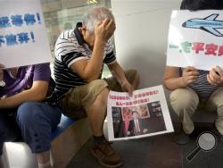 Family members of passengers aboard the missing Malaysia Airlines Flight 370 hold signs as they protest outside the company's offices in Beijing, bout a dozen Chinese relatives of passengers protested outside the Malaysia Airlines offices in Beijing on Thursday.(AP Photo/Mark Schiefelbein)