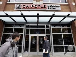 In this Nov. 9, 2015, file photo, pedestrians walk past a still-closed Chipotle restaurant in Seattle. An outbreak of E. coli that originated in the Pacific Northwest has spread south and east and has now infected people in six states. New cases have been reported in California, New York and Ohio, the Centers for Disease Control and Prevention said Friday, Nov. 20, 2015. (AP Photo/Elaine Thompson, File)