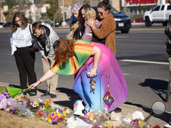 A couple embrace near a makeshift display of bouquets of flowers on a corner near the site of a mass shooting at a gay bar Monday, Nov. 21, 2022, in Colorado Springs, Colo. (AP Photo/David Zalubowski)