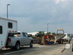 In this Monday, Aug. 31, 2015 photo, a tow truck removes a chuck wagon that overturned on the Interstate 30 bridge in Little Rock, Ark., while being towed behind a car. The wagon was en route to the annual Chuckwagon Races planned this weekend in Clinton, Ark. (Tami Mcham via AP)