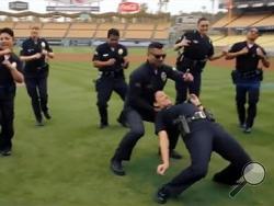 In this undated frame from video provided by the Los Angeles Police Department, LAPD officers dance on the field at Dodger Stadium in Los Angeles. (Los Angeles Police Department via AP) 