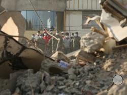 Rescue workers stand behind rubble after an earthquake in Portoviejo, Ecuador, Sunday, April 17, 2016. Rescuers pulled survivors from the rubble Sunday after the strongest earthquake to hit Ecuador in decades flattened buildings and buckled highways along its Pacific coast on Saturday night. The magnitude-7.8 quake killed hundreds of people. (AP Photo/Carlos Sacoto)