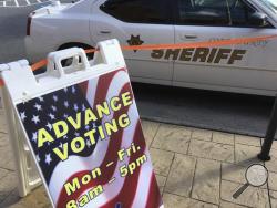 A sign displays absentee voting hours at a voting site in Marietta, Ga., as a Cobb County Sheriff deputy sits in his vehicle, Monday, Oct. 17, 2016, in Marietta, Ga. Monday was the first day people could vote absentee in the state. Facing unprecedented warnings of a "rigged" election from Donald Trump, state officials around the country are rushing to reassure the public, and some are taking subtle steps to boost security at polling places because of the passions whipped up by the race. (AP Photo/Mike Stewa