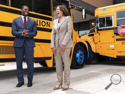 FILE - Vice President Kamala Harris, right, laughs with Environmental Protection Agency Administrator Michael Regan, during a tour of electric school buses at Meridian High School in Falls Church, Va., May 20, 2022. Nearly 400 school districts spanning all 50 states are receiving grants totaling nearly $1 billion to purchase nearly 2,500 "clean" school buses under a new federal program. The Biden administration is making the grants available as part of a wider effort to accelerate the transition to zero emi