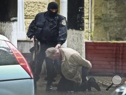 In this June 27, 2011 photo provided by the Moldova General Police Inspectorate, Teodor Chetrus is detained by a police officer in Chisinau, Moldova during a uranium-235 sting operation.