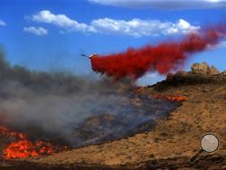 This Aug. 9, 2015 photo taken by Utah state firefighter Eli Peterson shows a firefighting plane making dropping retardant over a fire in Owyhee County, Idaho.