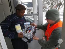 Louis Singleton receives water filters, bottled water and a test kit from Michigan National Guard Specialist Joe Weaver as clean water supplies are distributed to residents, Thursday, Jan. 21, 2016 in Flint, Mich. The National Guard, state employees, local authorities and volunteers have been distributing lead tests, filters and bottled water during the city's drinking water crisis. (AP Photo/Paul Sancya)