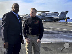 Defense Secretary Lloyd Austin, left, talks with the commanding officer of the USS Gerald R. Ford, Navy Capt. Rick Burgess, during an unannounced visit to the ship on Wednesday, Dec. 20, 2023. The USS Gerald R. Ford has been sailing just a few hundred miles off the coast of Israel to prevent the Israel-Hamas war from expanding into a regional conflict. (AP Photo/Tara Copp)