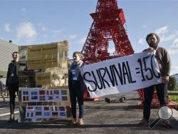 Representatives of NGOs display a banner in front of a reproduction of the Eiffel towerat the COP21, United Nations Climate Change Conference, in Le Bourget north of Paris, Friday, Dec. 4, 2015. Many activists and negotiators from small island nations want a final climate accord to aim at a keeping global warming to 1.5 degrees worldwide by 2100, instead of 2 degrees.(AP Photo/Michel Euler)
