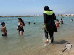 In this image made from video, Nissrine Samali, 20, gets into the ocean wearing traditional Islamic dress, in Marseille, France, Thursday, Aug. 4, 2016. (AP Photo)